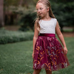 Twirling pose in white lace and burgundy floral embroidered dress
