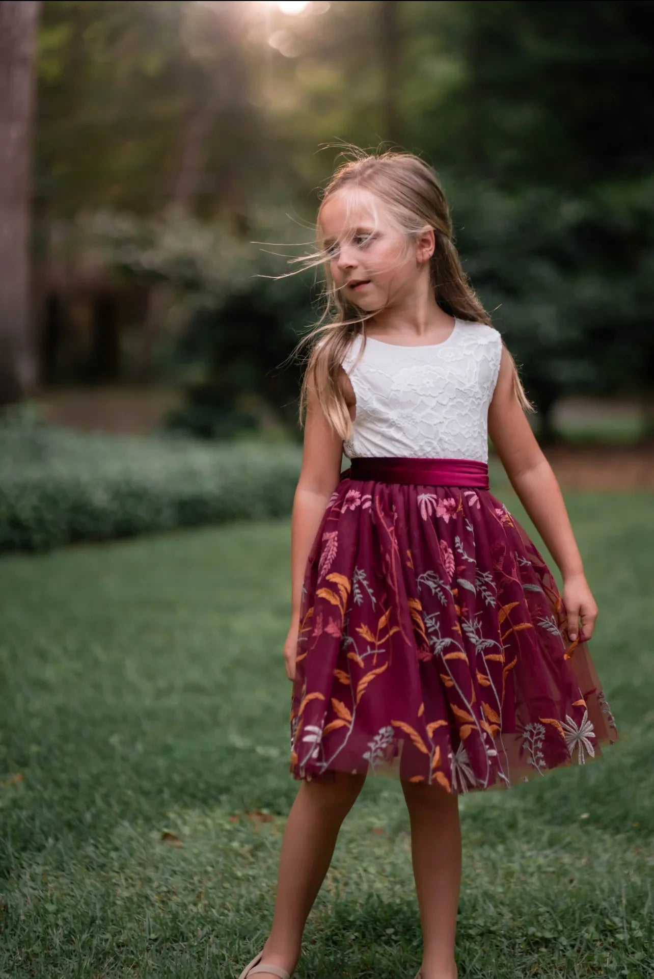 Twirling pose in white lace and burgundy floral embroidered dress