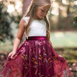 Girl wearing burgundy embroidered flower girl dress with white lace bodice