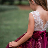 Toddler girl in burgundy flower girl dress walking outdoors