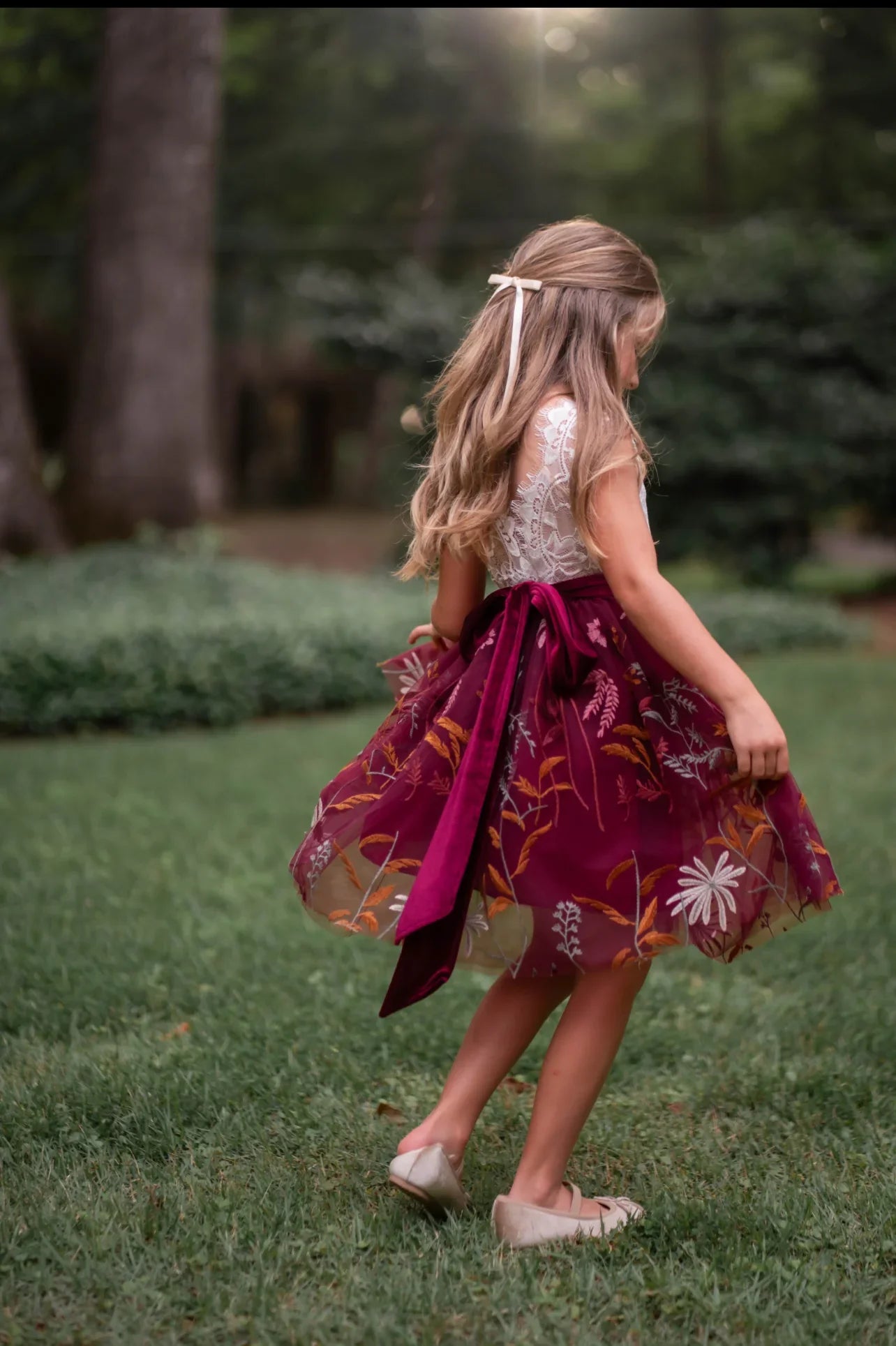 White lace and burgundy floral embroidered dress on little girl twirling