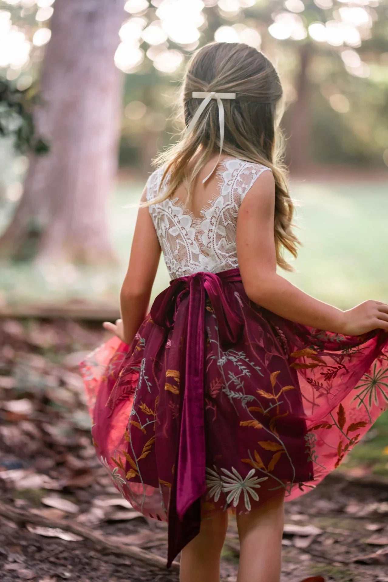 Back view of white lace and burgundy velvet sash with floral embroidery