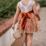 Back view of white lace and burnt orange embroidered fall flower girl dress tied with a velvet sash