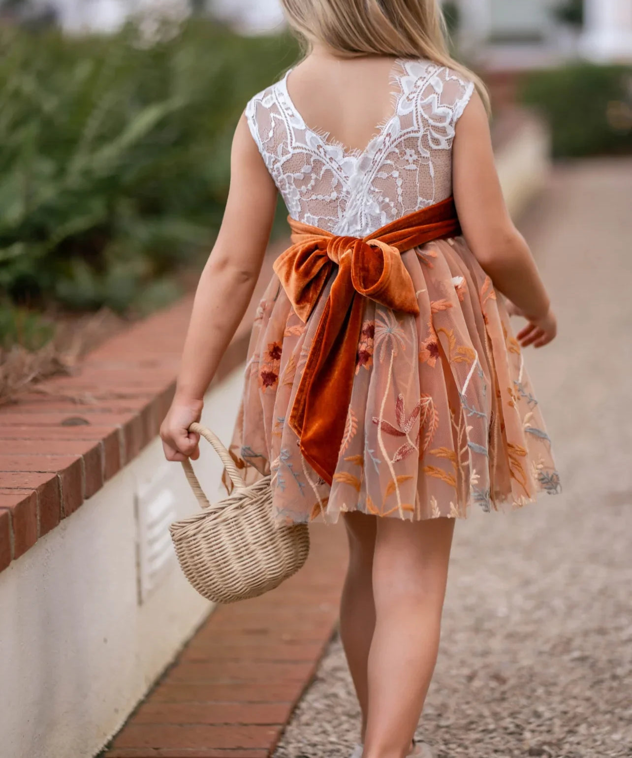 Back view of white lace and burnt orange embroidered fall flower girl dress tied with a velvet sash