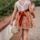 Back view of white lace and burnt orange embroidered fall flower girl dress tied with a velvet sash