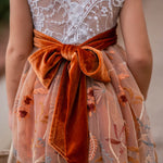 Close-up of V-back lace bodice and large burnt orange velvet bow on girls fall dress