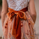 Close-up of V-back lace bodice and large burnt orange velvet bow on girls fall dress