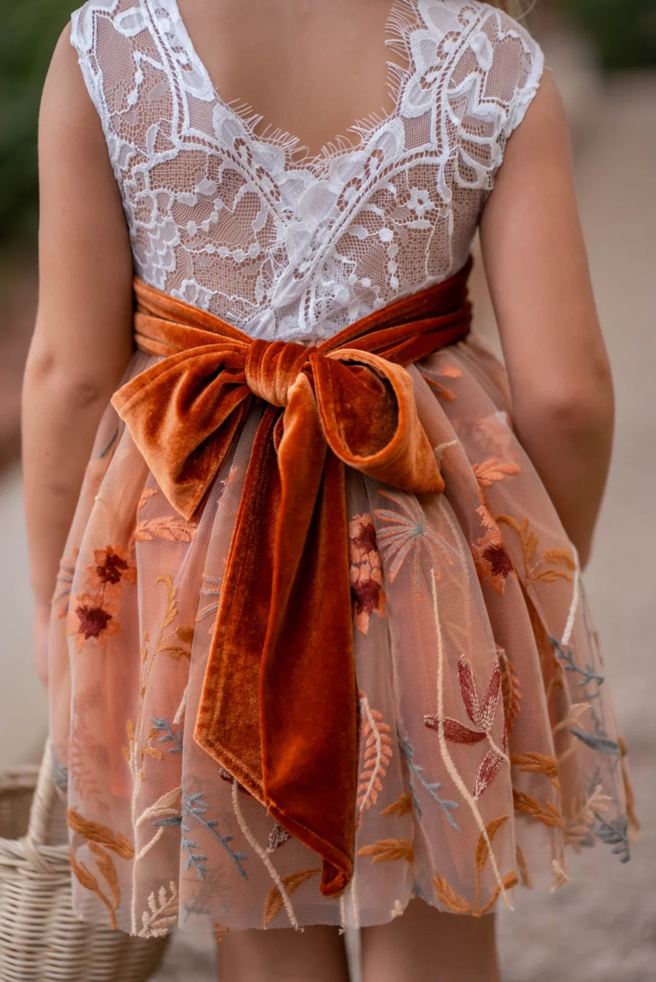 Close-up of V-back lace bodice and large burnt orange velvet bow on girls fall dress