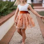 Girl twirling in white lace and burnt orange floral embroidered knee-length dress