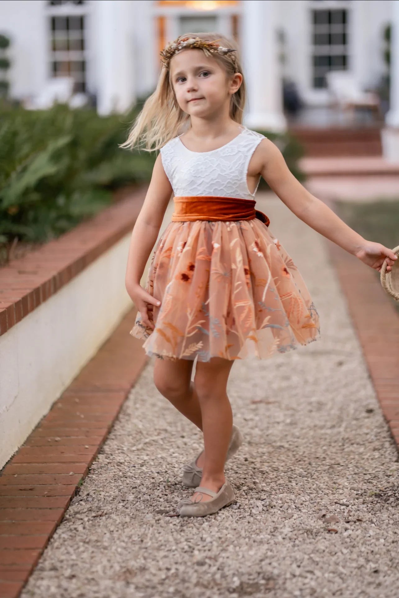 Girl twirling in white lace and burnt orange floral embroidered knee-length dress