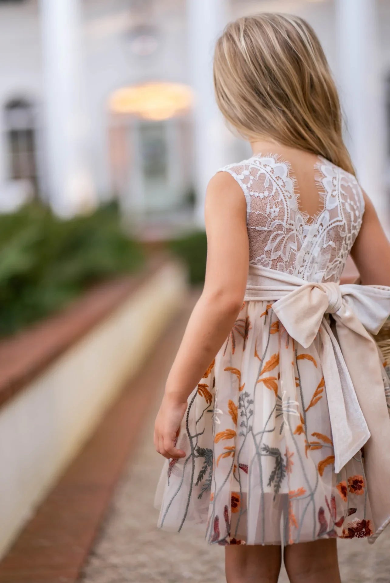 Little girl twirling in white lace and champagne floral embroidered fall dress
