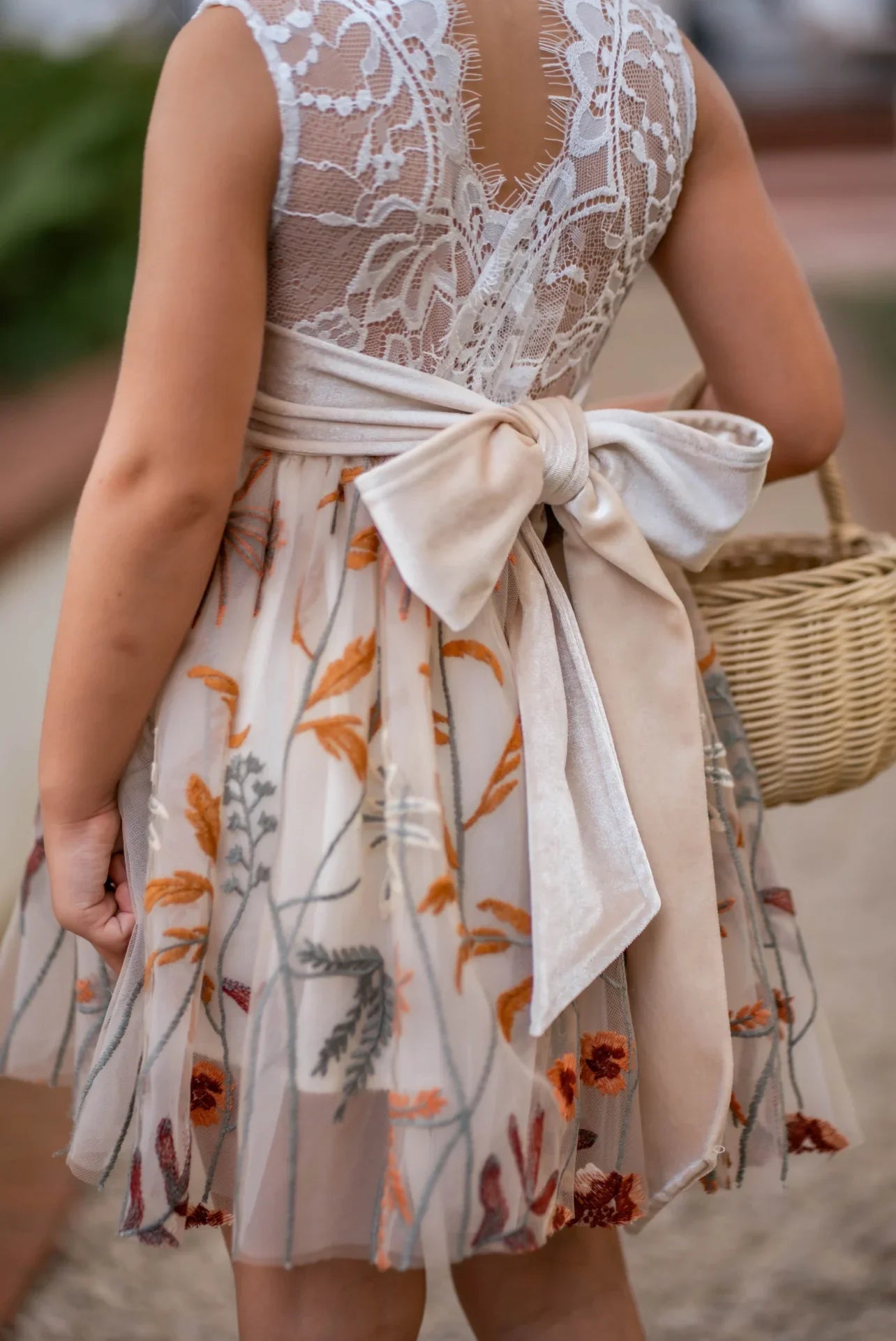 Close-up of champagne velvet sash on girls’ embroidered knee-length dress
