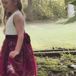 Video of girl twirling in burgundy floral embroidered flower girl dress with white lace bodice and velvet sash”

